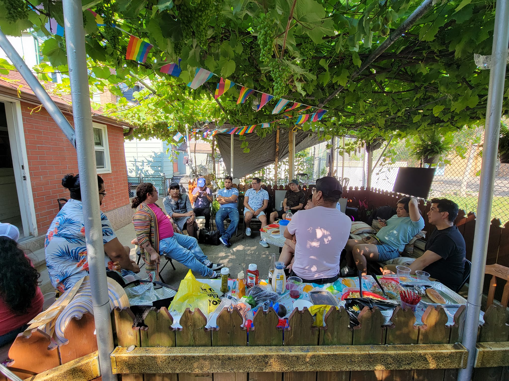 Community members in a backyard circle with pride flags